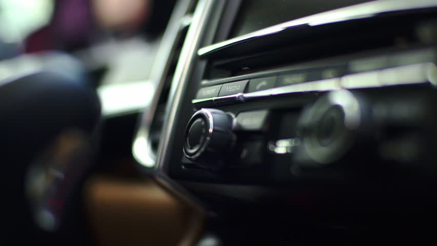 Driver cranks car stereo louder, focus on hand and volume knob in close view