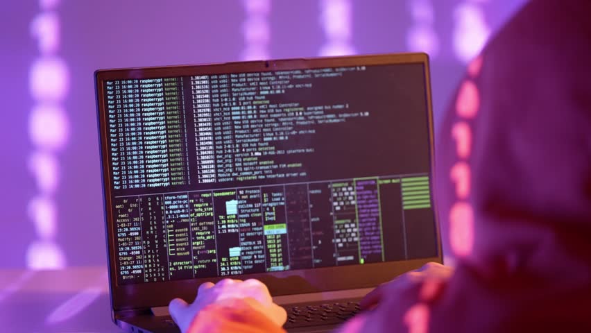 A hooded figure faces a laptop displaying terminal code, surrounded by glowing binary light in a violet-lit space, symbolizing system breach and deep-layer digital operations