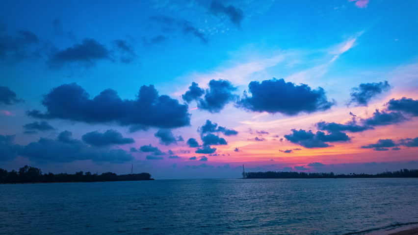 Time lapse A stunning sunset over a calm beach, with golden sunlight reflecting on the water. The dramatic sky, filled with soft clouds, adds depth and contrast to the peaceful coastal scene.