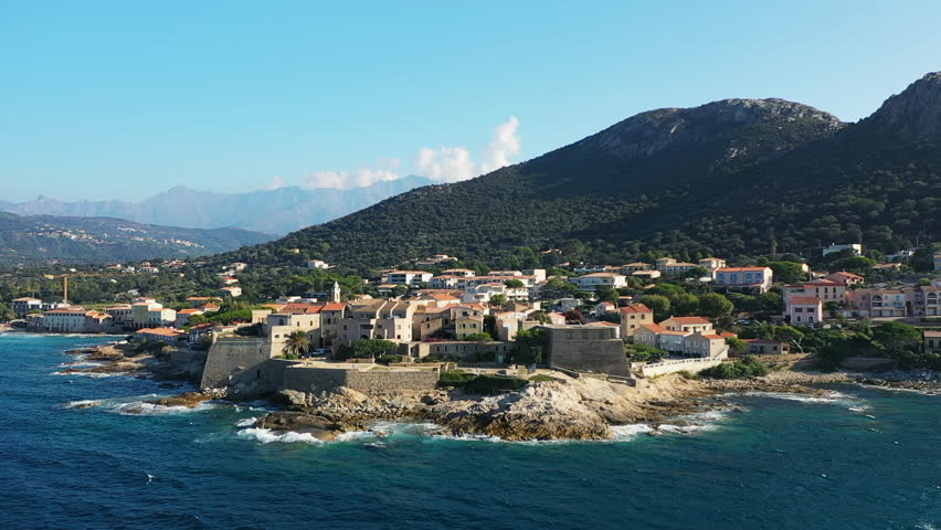 The panoramic view reveals Calvi and its medieval fort near the mountains, in Europe, in France, in Corsica, on the edge of the Mediterranean Sea, in summer, on a sunny day.