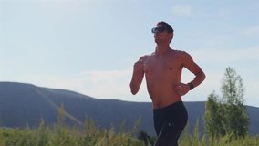 Under the bright sun, a young man with an athletic build runs along a mountain trail, pressing smartwatch to track the results of his interval training, monitoring his heart rate, pace, and distance. - Powered by Shutterstock - Get 15% off with code: PIKWIZARD15