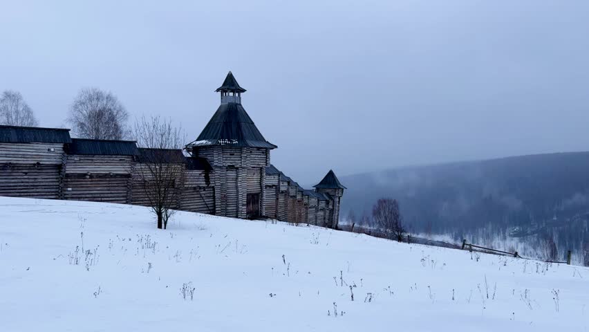 A log fortress wall covered with snow after a blizzard. Scenery for the film "The Heart of Parma" among snow-covered forests, hills and mountains in Perm Krai, Russia. The crooked cross in the Lip.4K