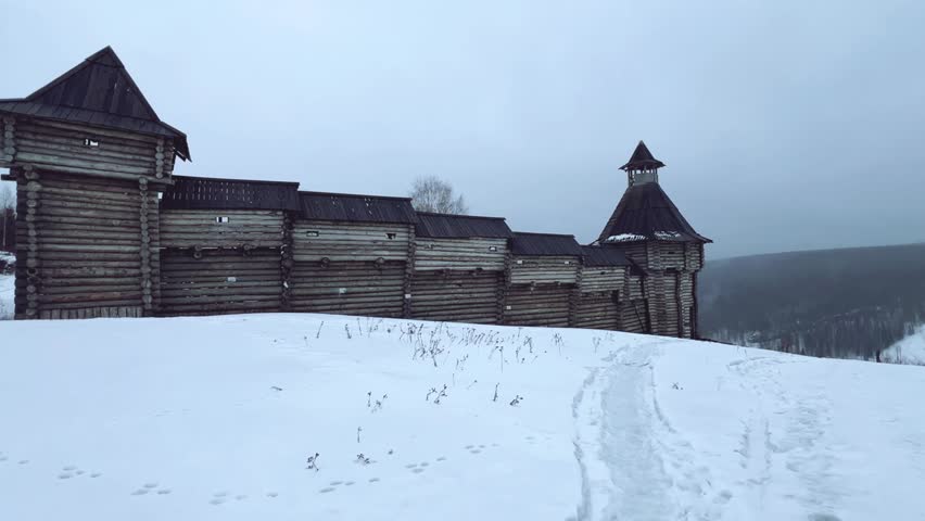 A log fortress wall covered with snow after a blizzard. Scenery for the film "The Heart of Parma" among snow-covered forests, hills and mountains in Perm Krai, Russia. The crooked cross in the Lip.4K
