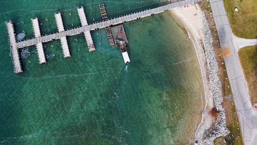 Top-down aerial view of wooden piers and breakwaters in clear Lake Michigan waters near a sandy shoreline in Michigan’s Upper Peninsula