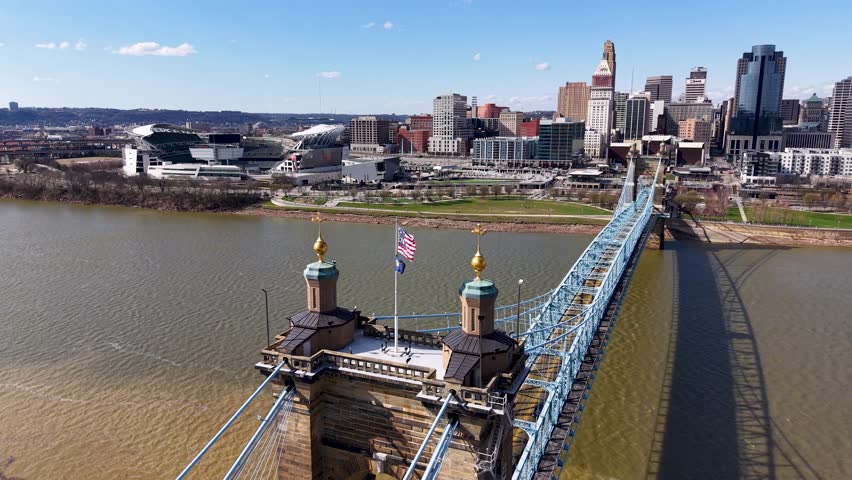 Cinematic drone shot over the Roebling Bridge, revealing twin towers, American flags, and downtown Cincinnati’s skyline along the Ohio River