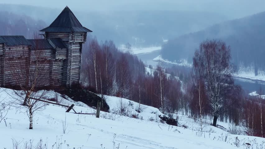 A log fortress wall covered with snow after a blizzard. Scenery for the film "The Heart of Parma" among snow-covered forests, hills and mountains in Perm Krai, Russia. The crooked cross in the Lip.4K