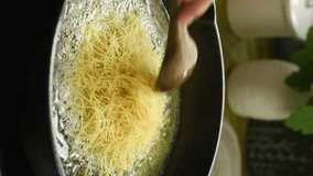 Vertical video. Cooking and stirring vermicelli in a pan. Stage of preparing pilaf. - Powered by Shutterstock - Get 15% off with code: PIKWIZARD15