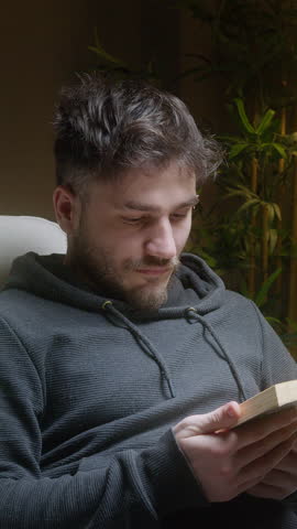 Young Man Peacefully Asleep in Armchair After Reading a Book at Night ,vertical video