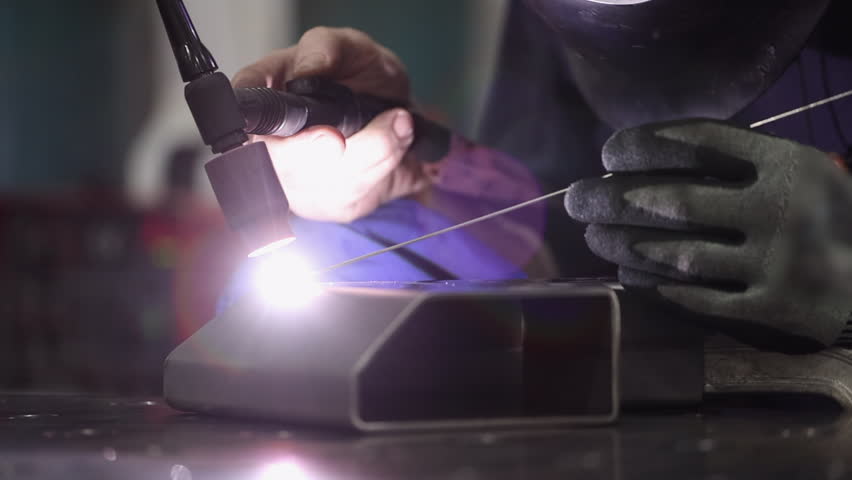 Low angle closeup manufacturing worker TIG welds aluminum corner part