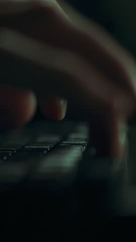 A hacker programmer types intently on a keyboard in a dark room. The soft glow from the screen illuminates their focused hand movements, reflecting a dedicated coding session at night