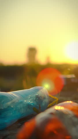 A man is carefully collecting plastic bottles and other debris along the shore of a pond during sunset. His actions highlight the importance of keeping nature clean and preserving the environment