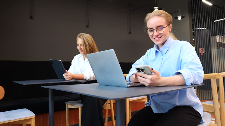  Two people work in a trendy cafe, using their devices and soaking up the lively atmosphere.