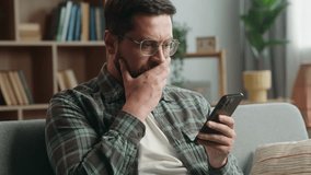 Caucasian adult man male guy at home living room nervous looking at mobile phone bad news amazed shocked close mouth with hand message from bank stressed smartphone notification online error scam - Powered by Shutterstock - Get 15% off with code: PIKWIZARD15