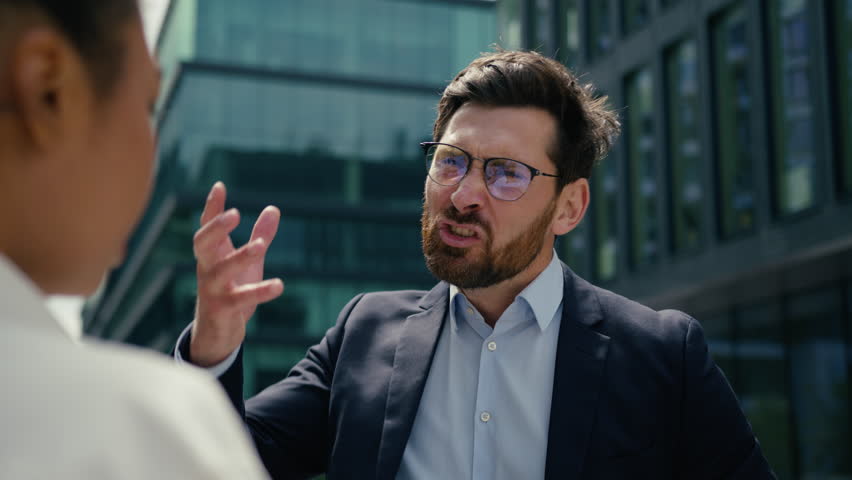 Angry authority Caucasian man businessman male boss leader yelling scolding to sad worried African American woman businesswoman female reprimand aggressive screaming problem business bullying in city