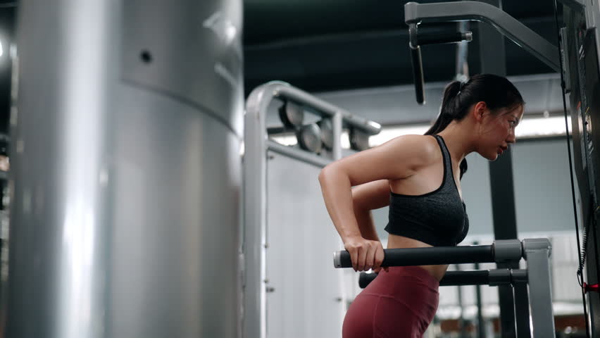 Focused fitness professional executing precise triceps dips on parallel bars, demonstrating strength and dedication within modern gym training environment