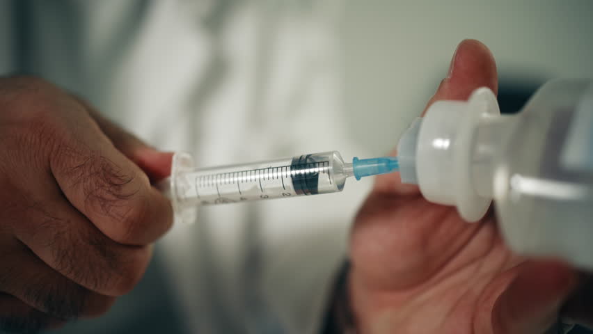 Close-Up of Doctor Drawing Medication into Syringe from Vial