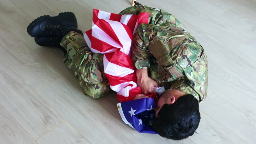 Veteran soldier experiencing severe post-traumatic stress disorder, lying on home floor while emotionally clutching American flag, representing invisible psychological wounds of military service