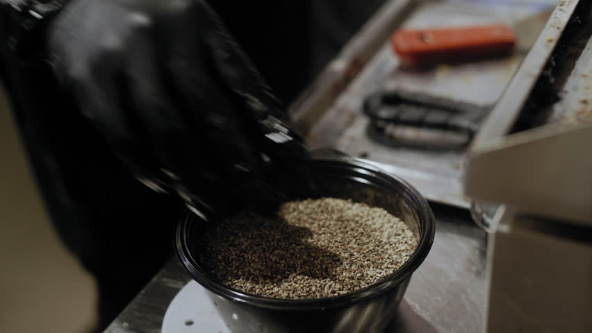 Close-up of a chef's hands seasoning a burger patty as it sizzles and smokes in a hot frying pan.