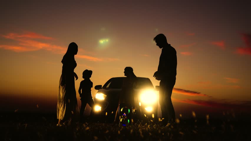 Cheerful family dancing in nature silhouettes. Children kids parents enjoying life with good music dancing next to car portable music speaker at sunset in evening. Road trip by car outdoor recreation