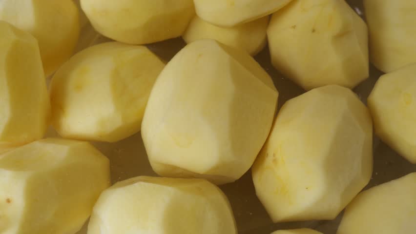 Peeled potatoes rotate slowly in closeup view.