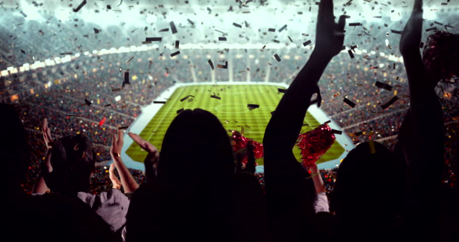 4K video of a lively stadium crowd at a nighttime soccer game, cheering confetti under bright stadium lights