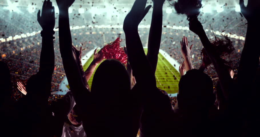 4K video of a lively stadium crowd at a nighttime soccer game, cheering confetti under bright stadium lights