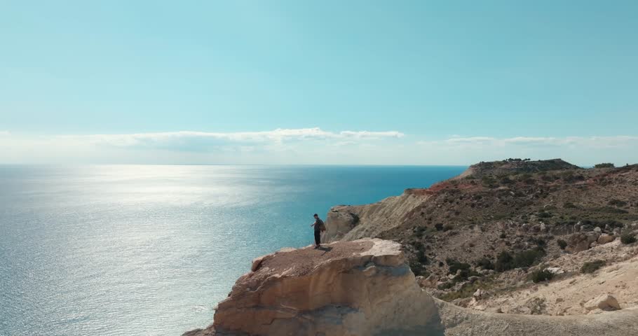 Aerial view of a man on the top of a rock on the birch of the sea. There is a feeling of freedom at the top after hiking along mountain trails on the birch ocean, tourism and roads. High quality 4k 