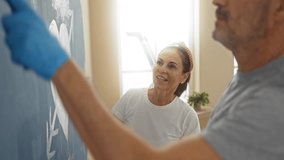 Middle-aged hispanic couple painting heart on wall in living room expressing love and creativity in new home interior together. - Powered by Shutterstock - Get 15% off with code: PIKWIZARD15