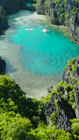 Turquoise Lagoons with boat and kayak in Miniloc Island. El Nido, Philippines. Palawan. Vertical view.