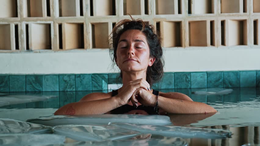 Beautiful Woman Dives into Cold Water of Swimming Pool with Ice Cubes for Body Health. Person in Bathtub Filled with Chilled Liquid for Youth Therapy. Winter Routine of Healthy Sportsman in Large Bath
