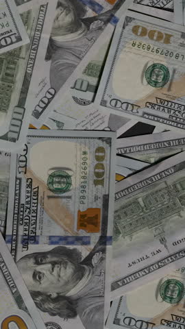 Vertical video. Hundred-dollar bills flutter and vanish out of the frame, leaving an empty black background, symbolizing the fleeting and transient nature of wealth