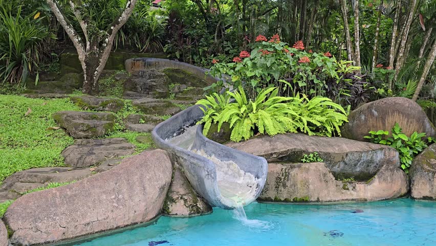 Asian child cute or kid girl enjoy with happy fun playing water slider on swimming pool or waterpark for fresh relax with exercise activity on summer holiday travel and family vacation. 