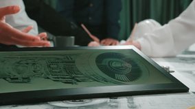 A business team collaborates in a modern office workspace, focusing on a digital tablet displaying a detailed engine design. Professional hands demonstrate teamwork and innovation. SACTR - Powered by Shutterstock - Get 15% off with code: PIKWIZARD15