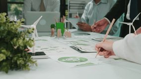 Business professionals collaborate on sustainable strategies using charts and models, showcasing innovation and teamwork in a modern office setting. SACTR - Powered by Shutterstock - Get 15% off with code: PIKWIZARD15