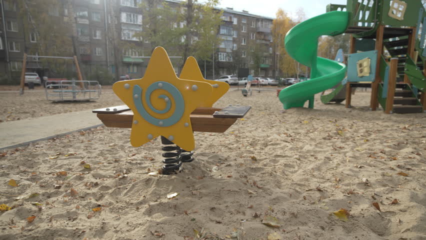 Star-shaped swing stands on sandy playground inviting kids to play. Unique and bright design adds charm to residential area on gloomy day