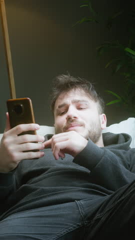 Frustrated Young Man Exhausted from Watching Short Videos on Phone, Feeling Wasted Time ,vertical video