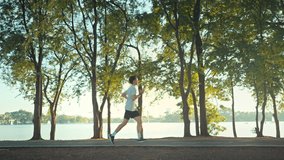 Side view - Attractive asian man jogging in the park on a background of trees with sunlight in sunset, Fitness Man Running, Training Run Workout. - Powered by Shutterstock - Get 15% off with code: PIKWIZARD15
