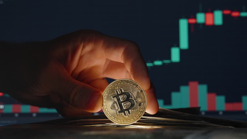 Hand Collecting Dollar Bills on the Table near Bitcoin Coin with Trading Chart in Background Showing Rising Market Trends