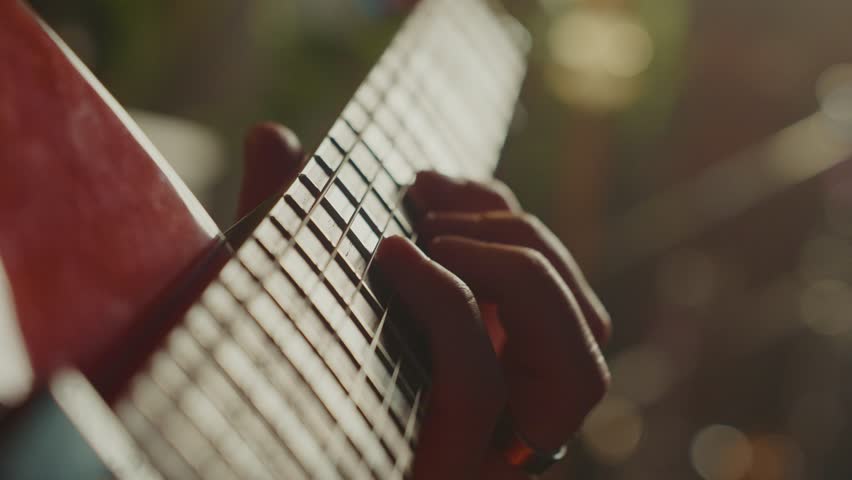Guitarist's skilled hands navigating red electric guitar's fretboard, capturing intricate finger movements and musical passion during detailed close up performance