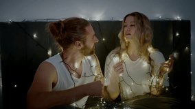 A couple enjoys a cozy evening together, playfully untangling string lights while decorating their bedroom. The warm atmosphere is enhanced by the soft glow of the lights. - Powered by Shutterstock - Get 15% off with code: PIKWIZARD15