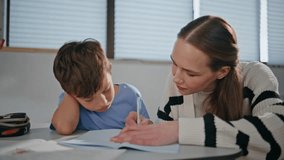 Attentive schoolteacher helping child boy at table in classroom closeup. Small pupil having lesson at elementary school. Lady educator writing copybook solving test with schoolchild. Education concept - Powered by Shutterstock - Get 15% off with code: PIKWIZARD15