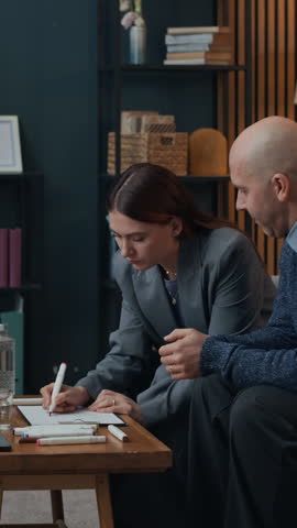 Vertical shot of Caucasian couple practicing drawing exercise during family therapy session