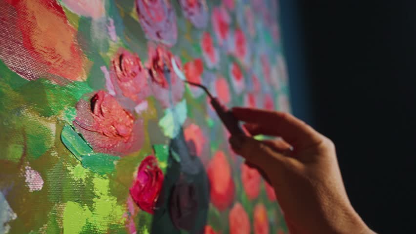 Artist hand gripping palette knife spreading thick white paint across vibrant canvas, layering textured impasto strokes to form delicate rose petals in spontaneous creative moment