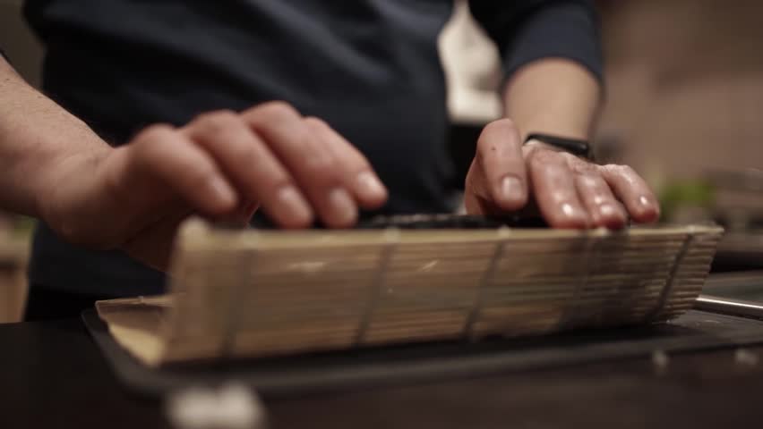 Chef Slicing Salmon and Preparing Sushi Rolls with Cheese and Cucumber