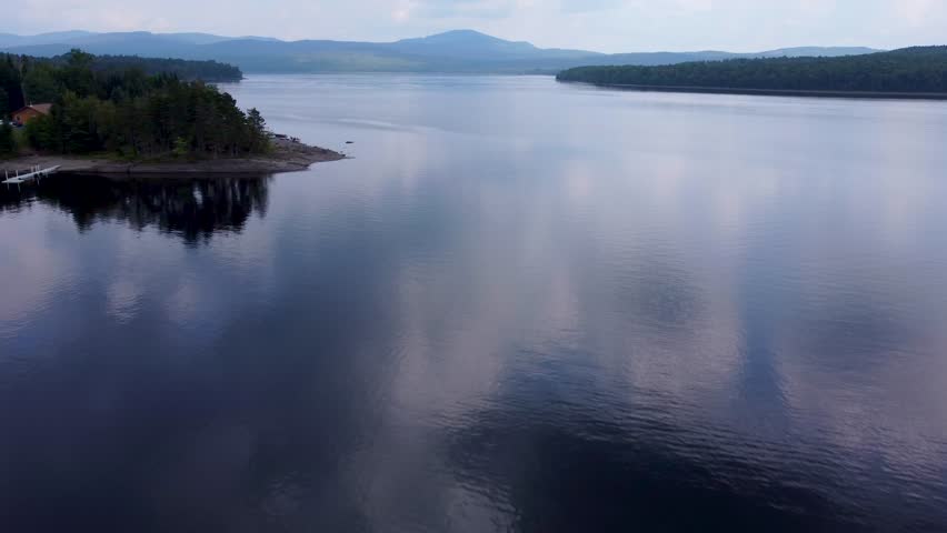 Aerial cinematic video of First Connecticut Lake with surrounding mountains and forest in Pittsburg, New Hampshire.