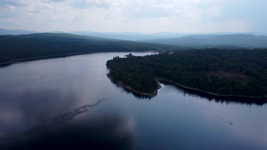 Aerial cinematic video of First Connecticut Lake with surrounding mountains and forest in Pittsburg, New Hampshire.