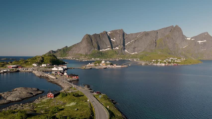 Enchanting coastal scenery showcases picturesque islands framed by majestic mountains under a clear sky. Tranquil waters reflect the stunning natural beauty of Lofoten Norways landscape.