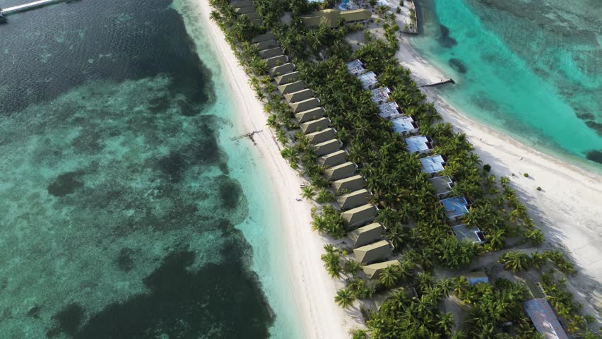 4K drone aerial view of luxury tropical beach resort with seafront villas, palm trees, swimming pools and turquoise ocean – paradise island vacation concept for tourism, travel, and real estate.
