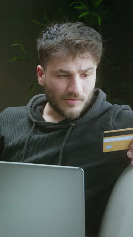 Excited Man Celebrating Online Purchase Success While Holding Credit Card and Using Laptop at Home ,vertical video