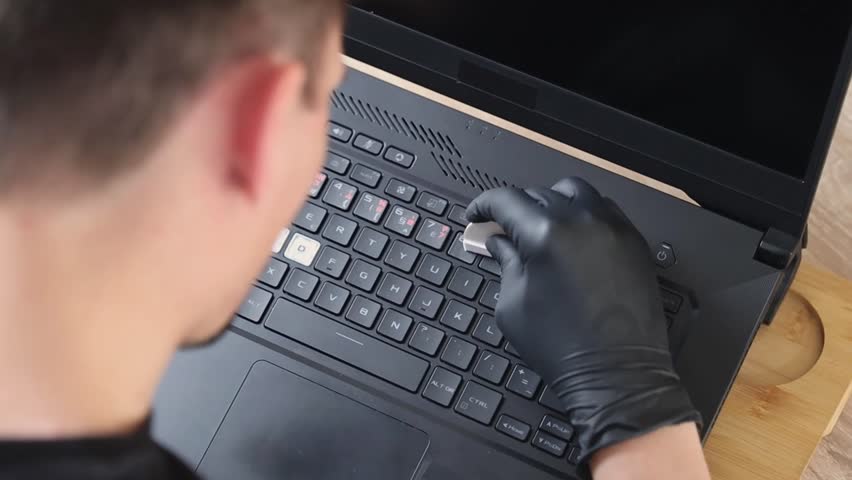 A man wipes a sticker on the laptop keyboard buttons.